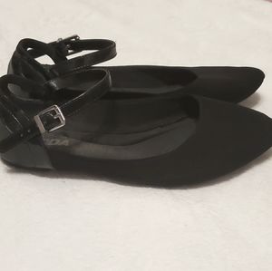 A pair of black flats with an ankle strap
